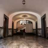 L�atrio di accesso � contraddistinto da pannelli di marmo grigio e nero sul pavimento e su parte delle mura laterali, quest�ultime scandite da una serie di porte in legno. Sul bianco soffitto a volta pendono due lanterne dorate che ci fanno luce fino al vano scala